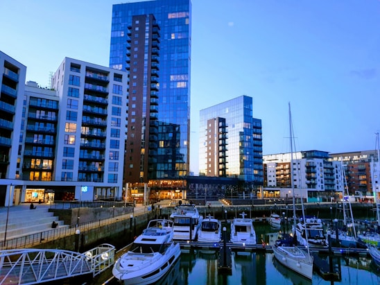 Elegant Malaysian skyline at dusk with luxury yachts and high-end apartments glowing under soft lights.