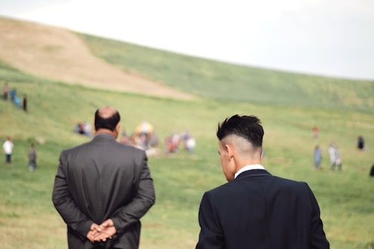 man in black suit jacket standing on green grass field during daytime in Ardabil Iran