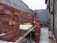 Stacks of red bricks are neatly arranged in a partially constructed building area. The walls are in various stages of construction, with some surfaces covered in unfinished plaster. There are tables holding bricks in preparation for further building work.