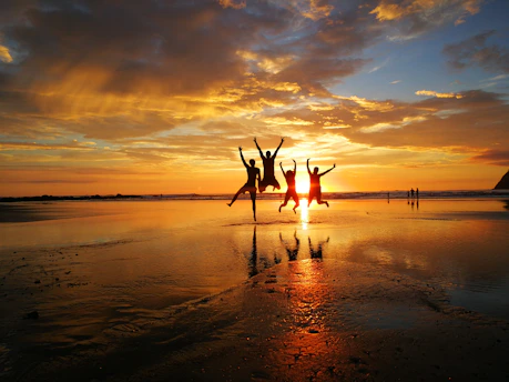people on beach in costa rica during sunset jumping