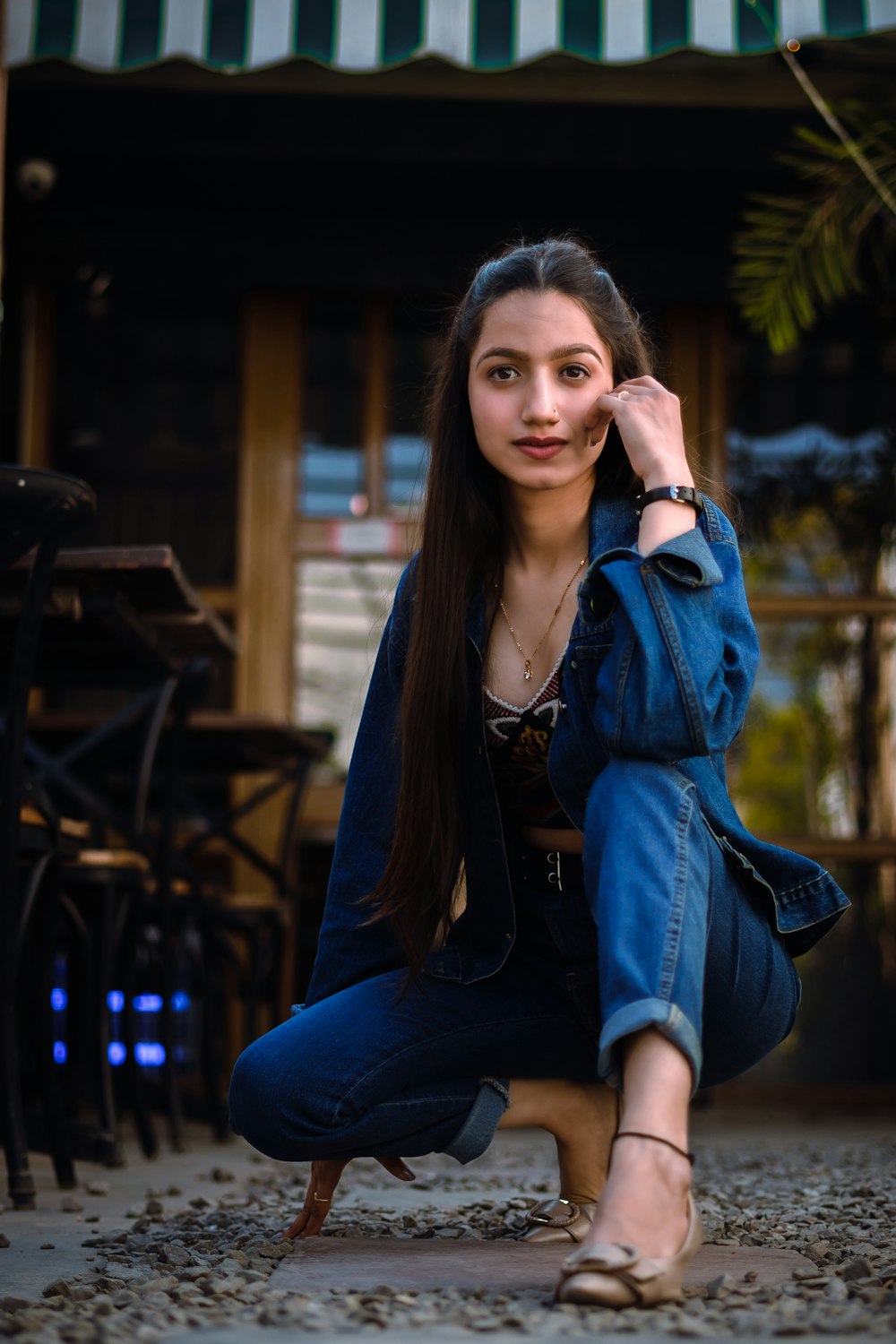 woman in blue denim jacket and blue denim jeans sitting on brown wooden bench