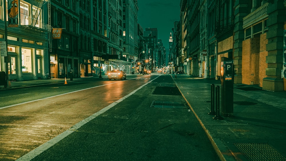 cars on road between high rise buildings during night time