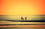 A cinematic frame of a sunset silhouette of a family walking along the beach.