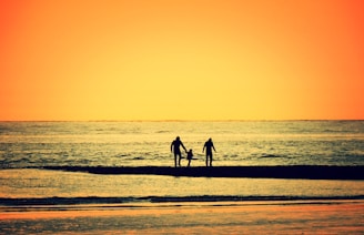 Minimalist black and white image of a family silhouette walking together at sunset.