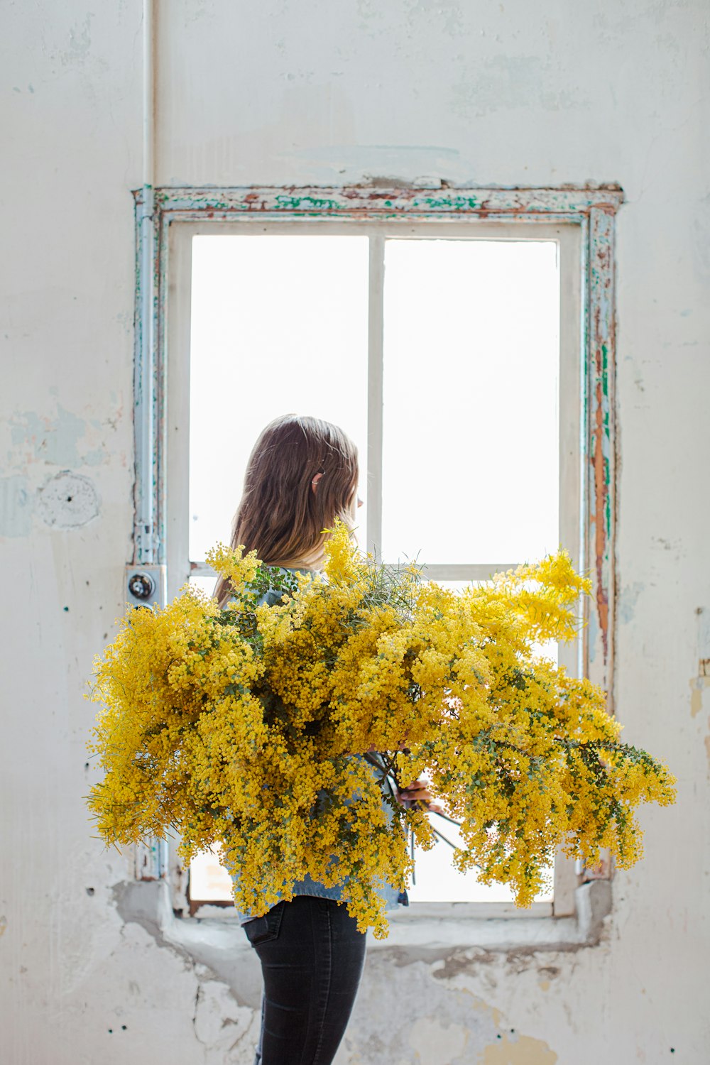 femme en chemise noire debout à côté de fleurs jaunes