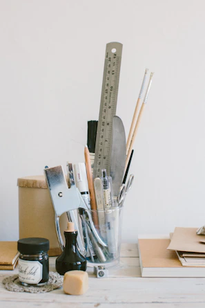 A collection of sustainable desk tools including a bamboo ruler, a metal clip, and a ceramic cup holding pencils.