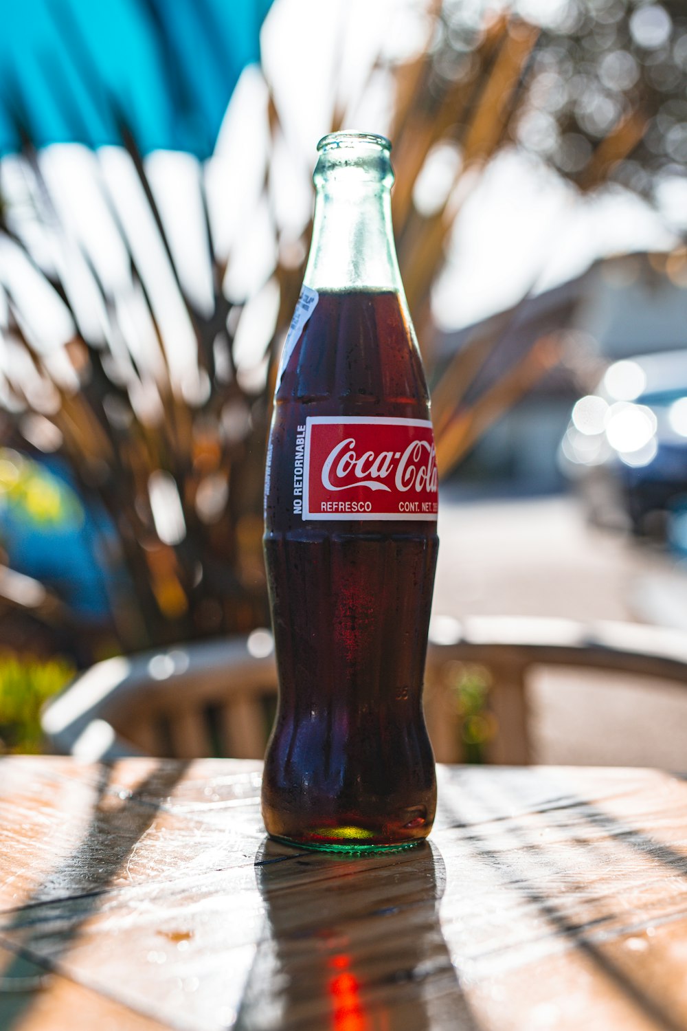 Botella de vidrio de Coca Cola sobre mesa de madera marrón