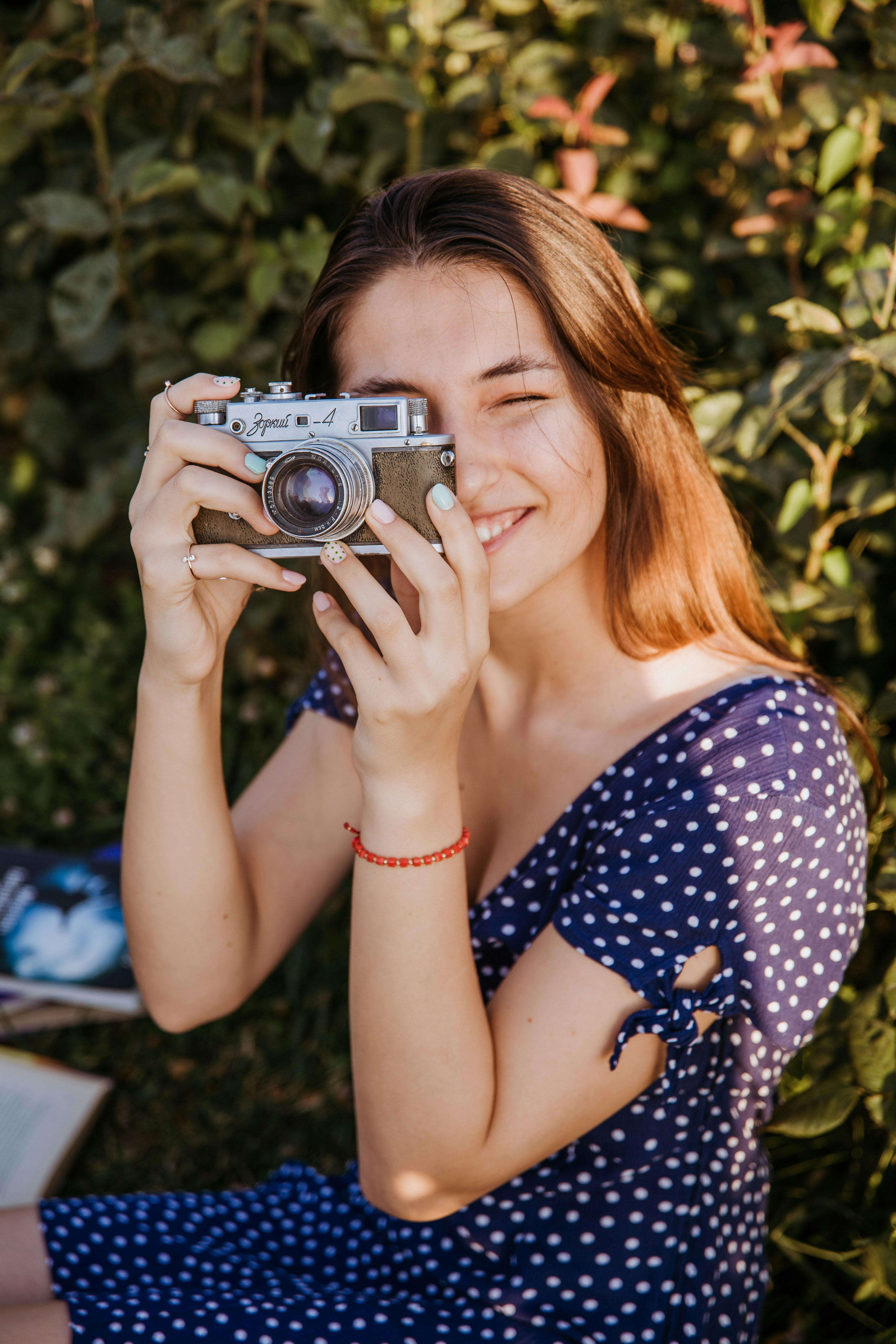 woman in blue and white polka dot shirt holding camera