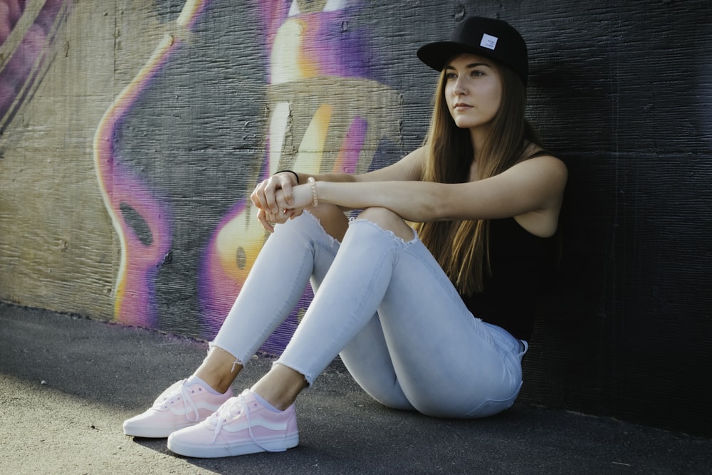 woman in black tank top and blue denim jeans wearing white boots sitting on road