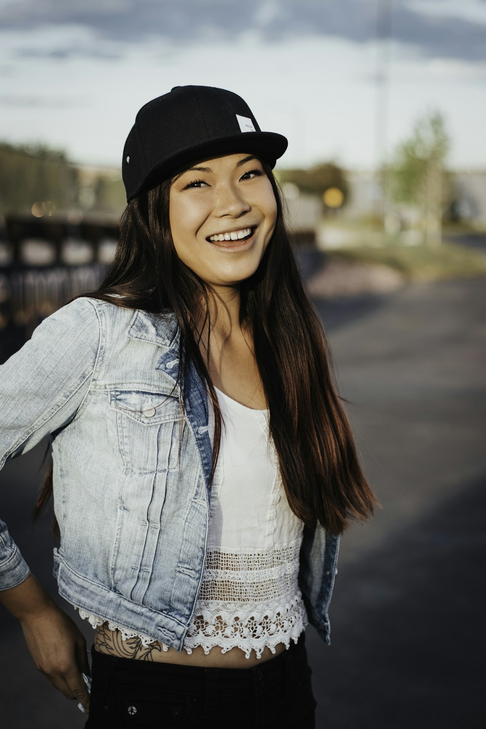 smiling woman in blue denim jacket and black hat