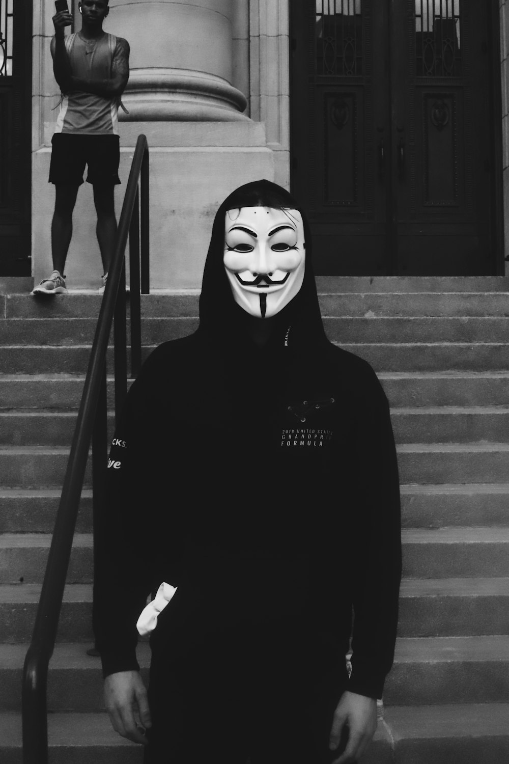 person in black hoodie wearing guy fawkes mask