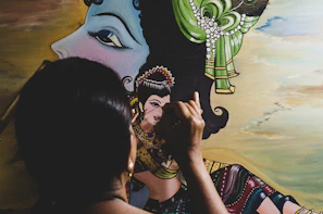 Artisan carefully painting fine details on a large paper-mâché catrina