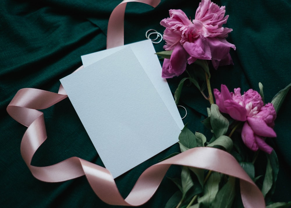 Tarjeta de felicitación blanca y rosa sobre textil verde