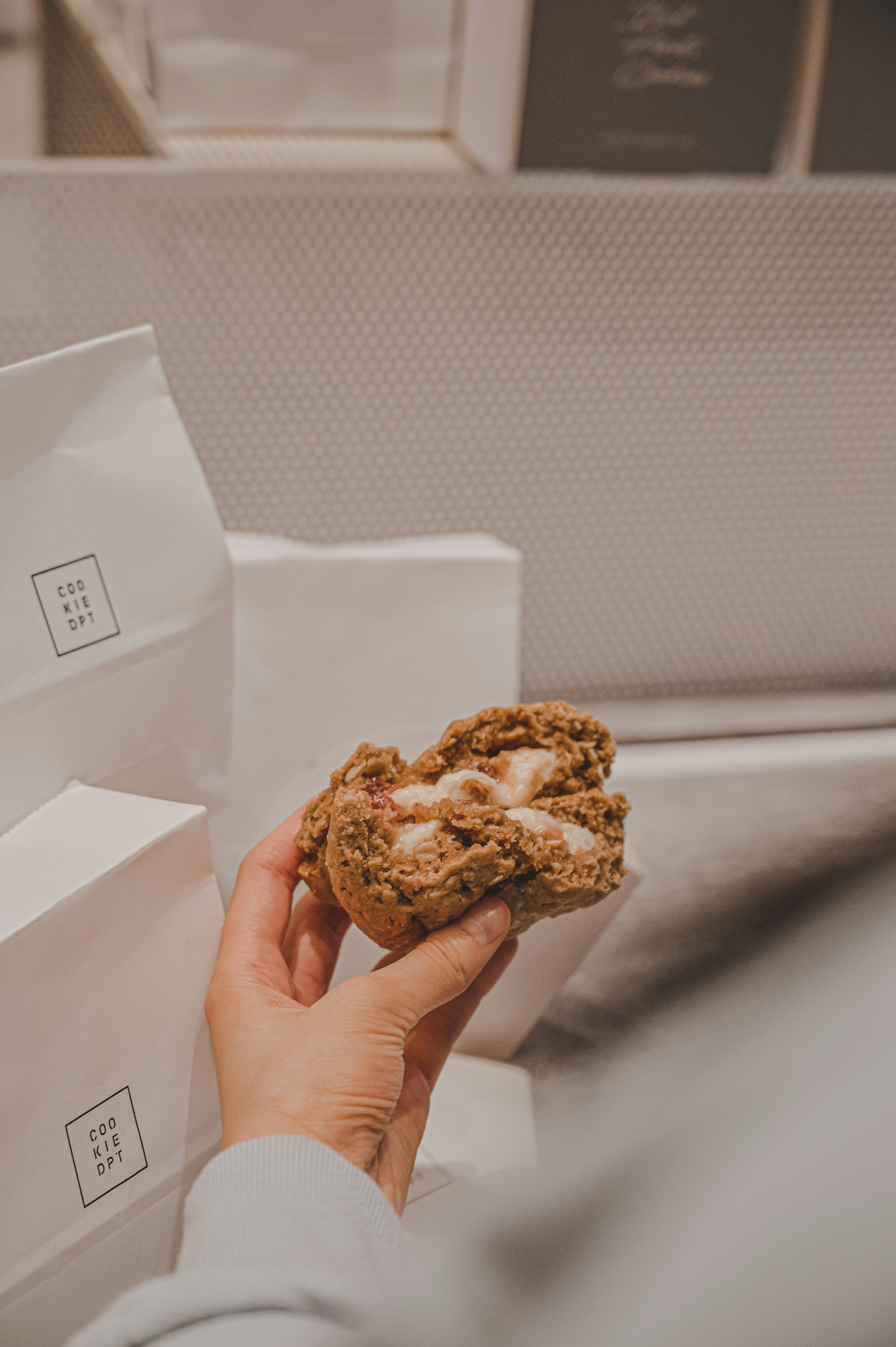 person holding brown cookies in white paper