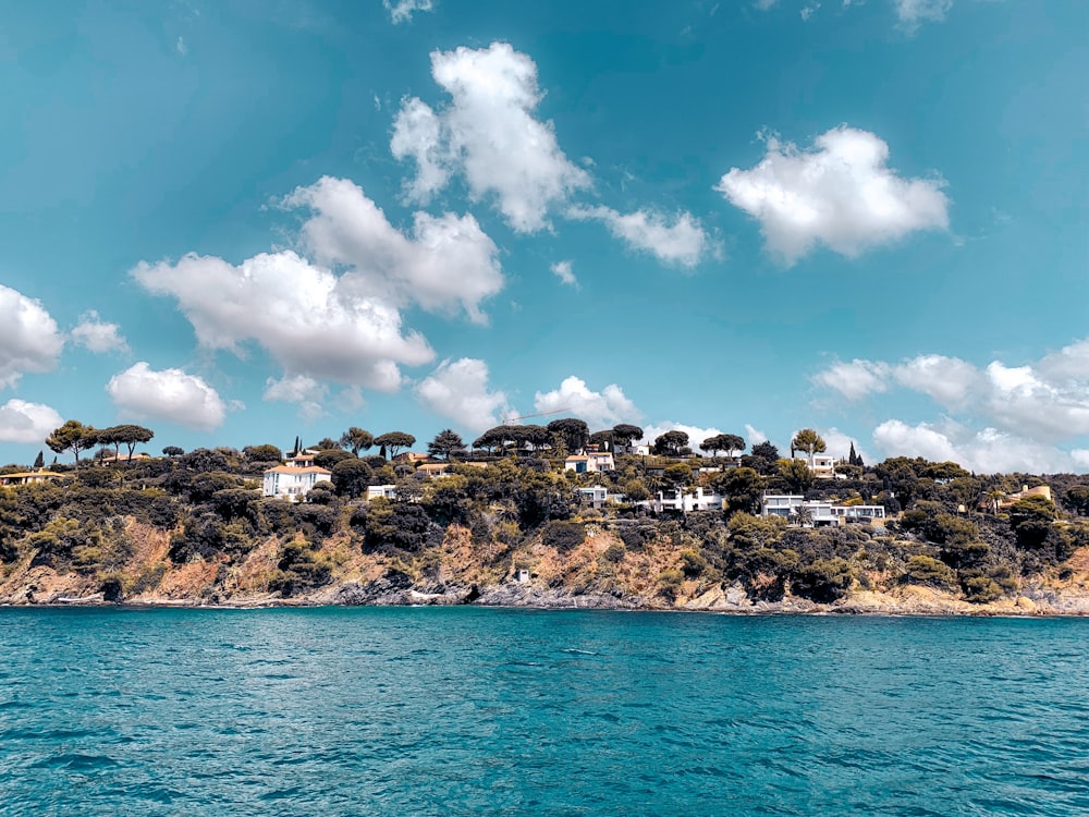 brown rocky mountain beside blue sea under blue and white cloudy sky during daytime