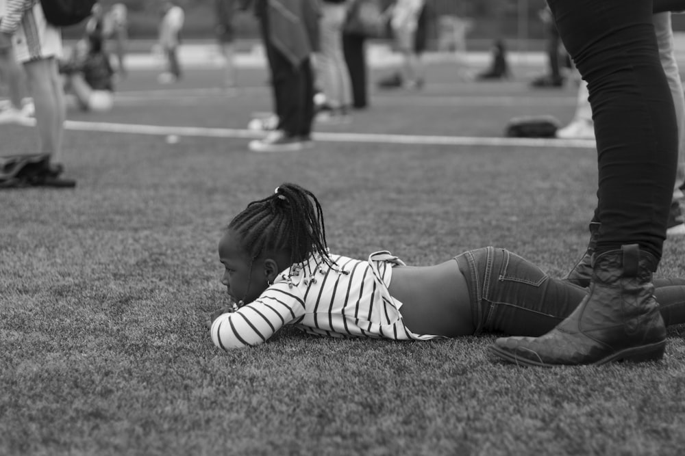 woman in white and black stripe long sleeve shirt and blue denim jeans lying on grass