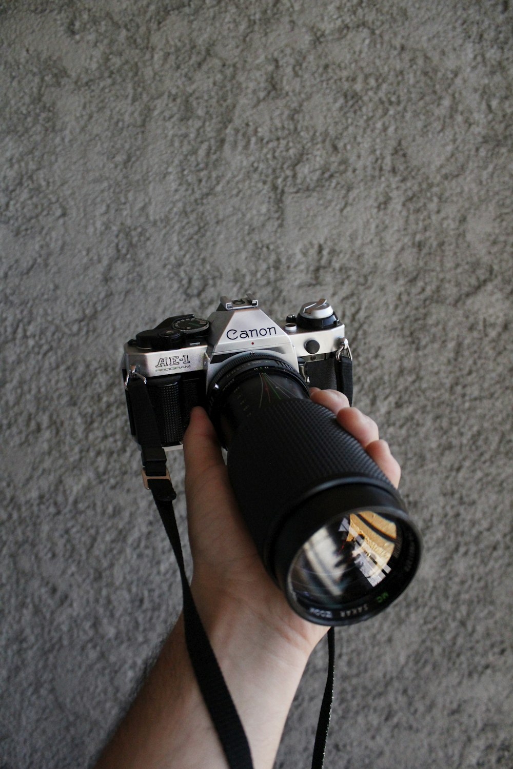 Hand holding a Canon AE1-Programm camera with a zoom lens
