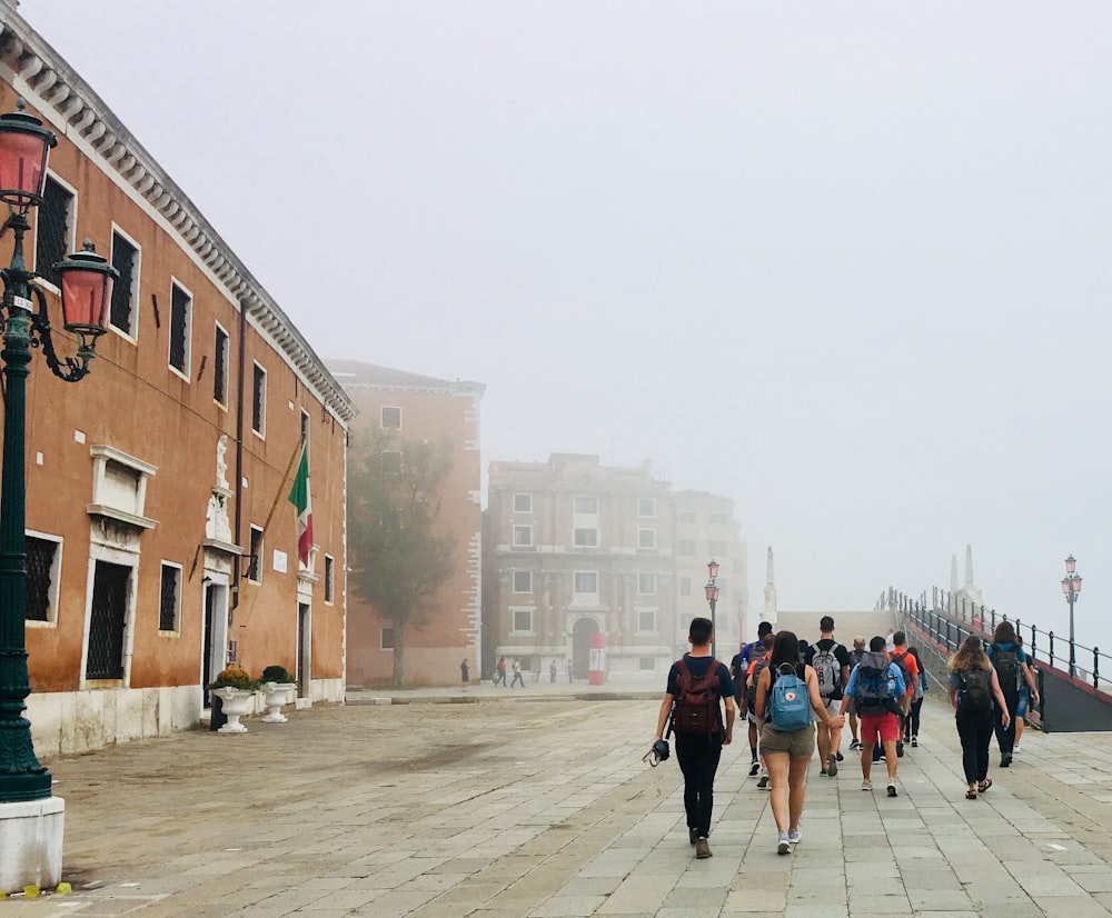 Personas caminando por la acera cerca de un edificio de hormigón marrón durante el día