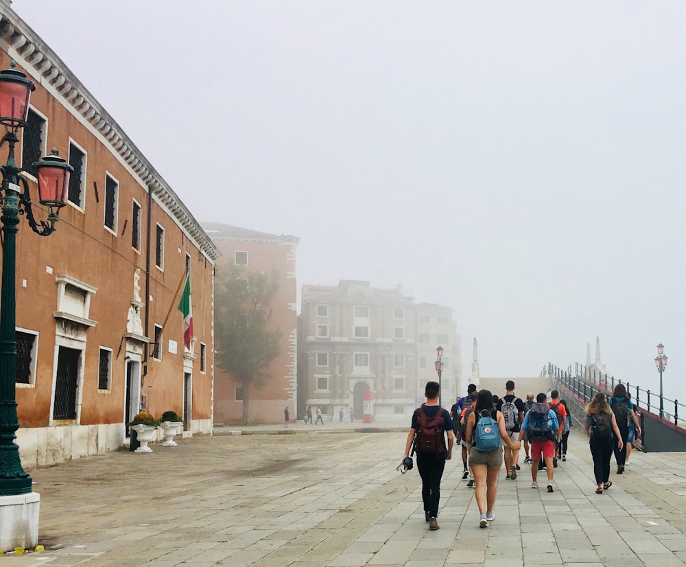 昼間、茶色のコンクリートの建物の近くの歩道を歩く人々