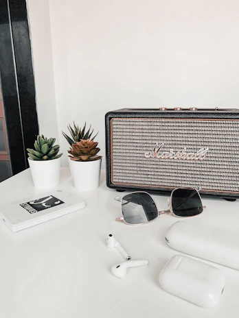 A SonicVibe speaker charging on a minimalist desk next to a laptop and coffee cup.