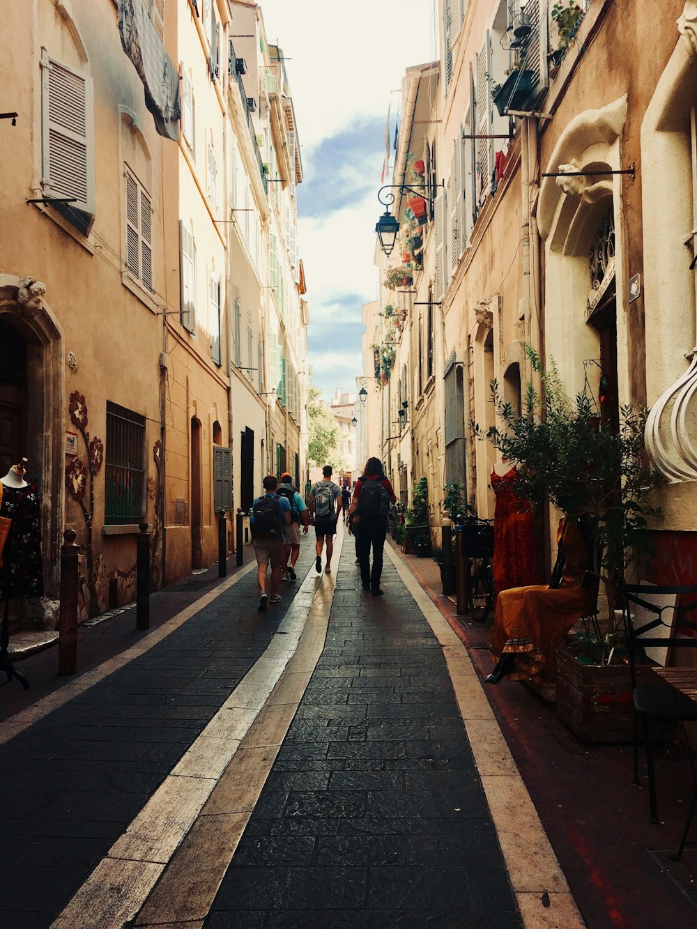 people walking on sidewalk between buildings during daytime