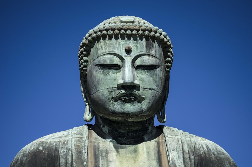 Statue en béton gris sous le ciel bleu pendant la journée