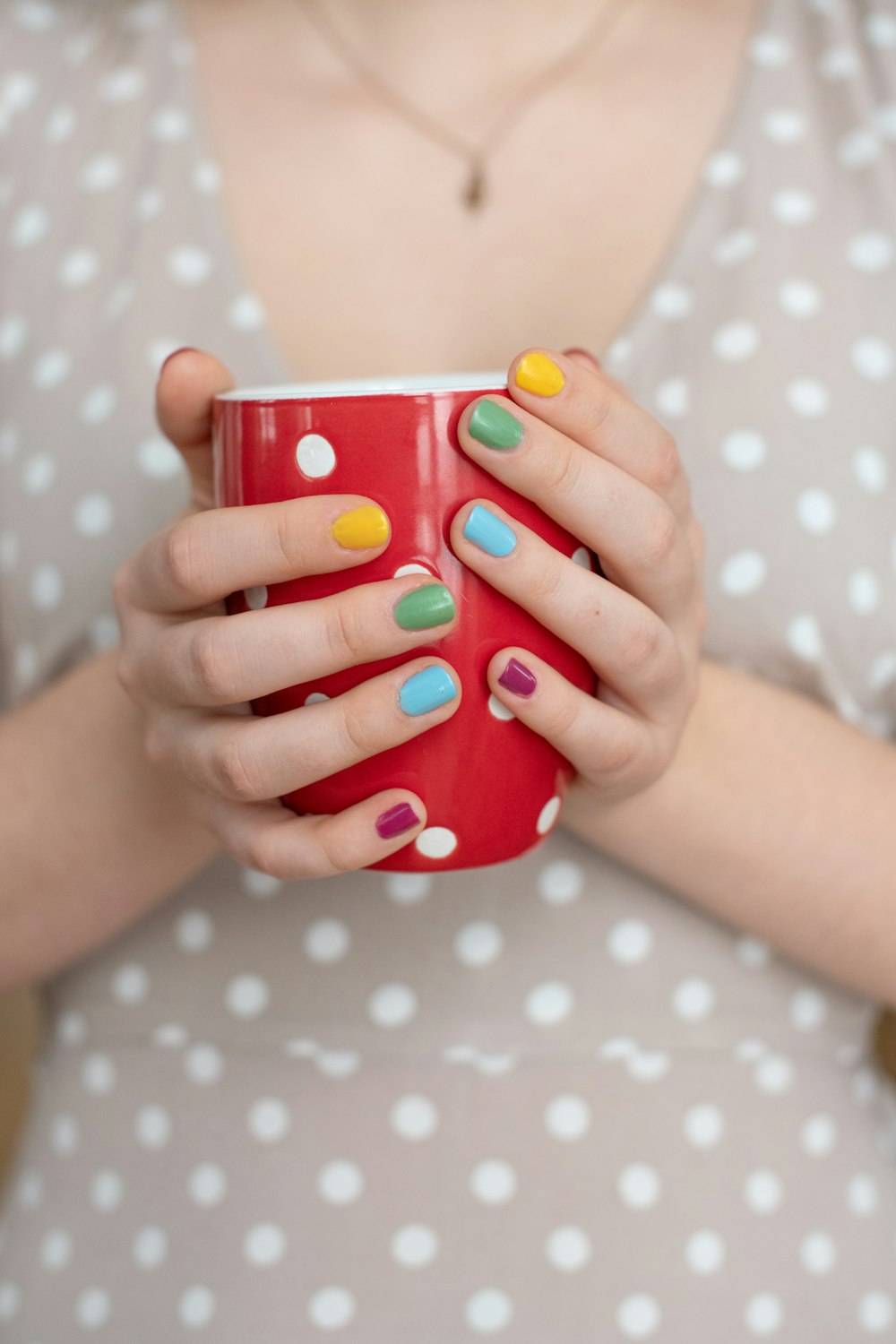 person holding red and white polka dot ceramic mug