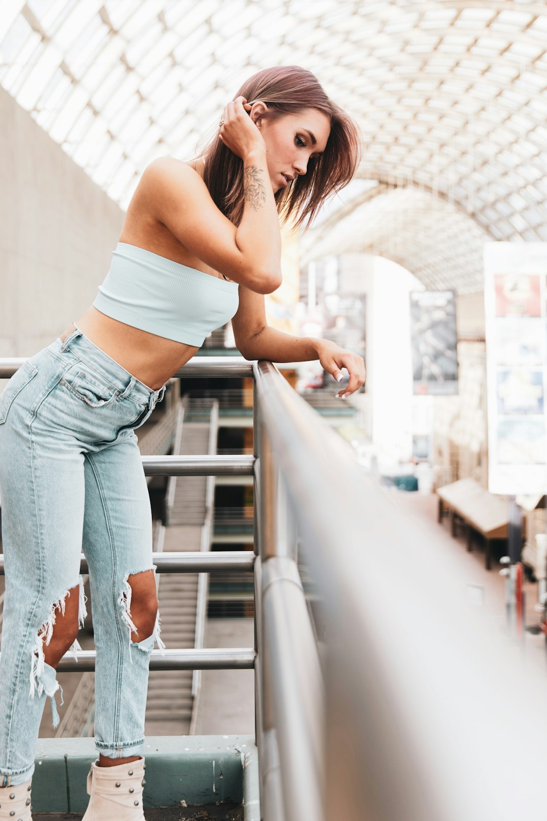 woman in white tank top and blue denim jeans standing on stairs