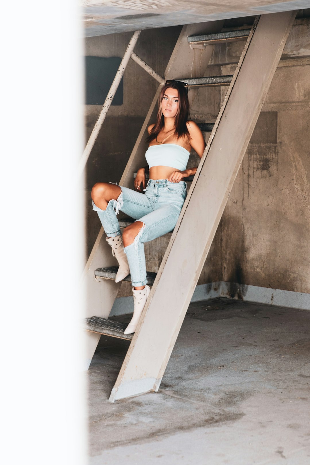 woman in white tank top and blue denim jeans sitting on stairs