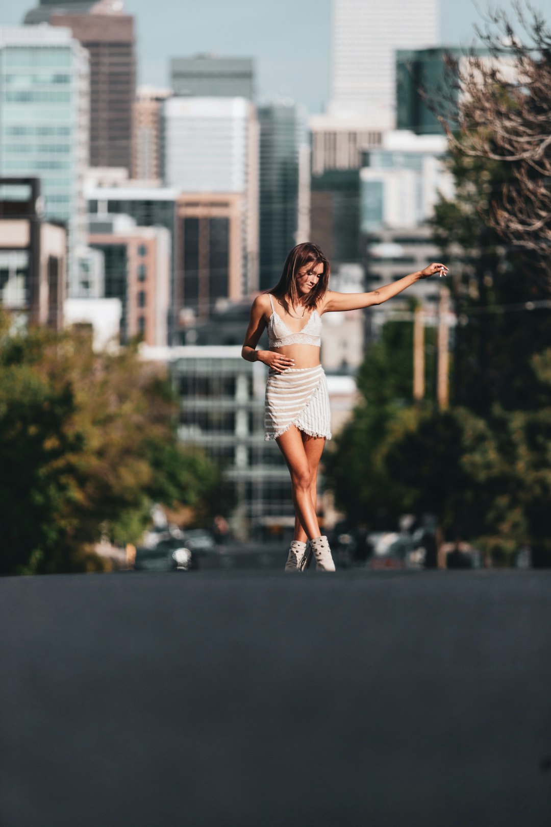 woman in white tank top and white shorts standing on black concrete pavement during daytime