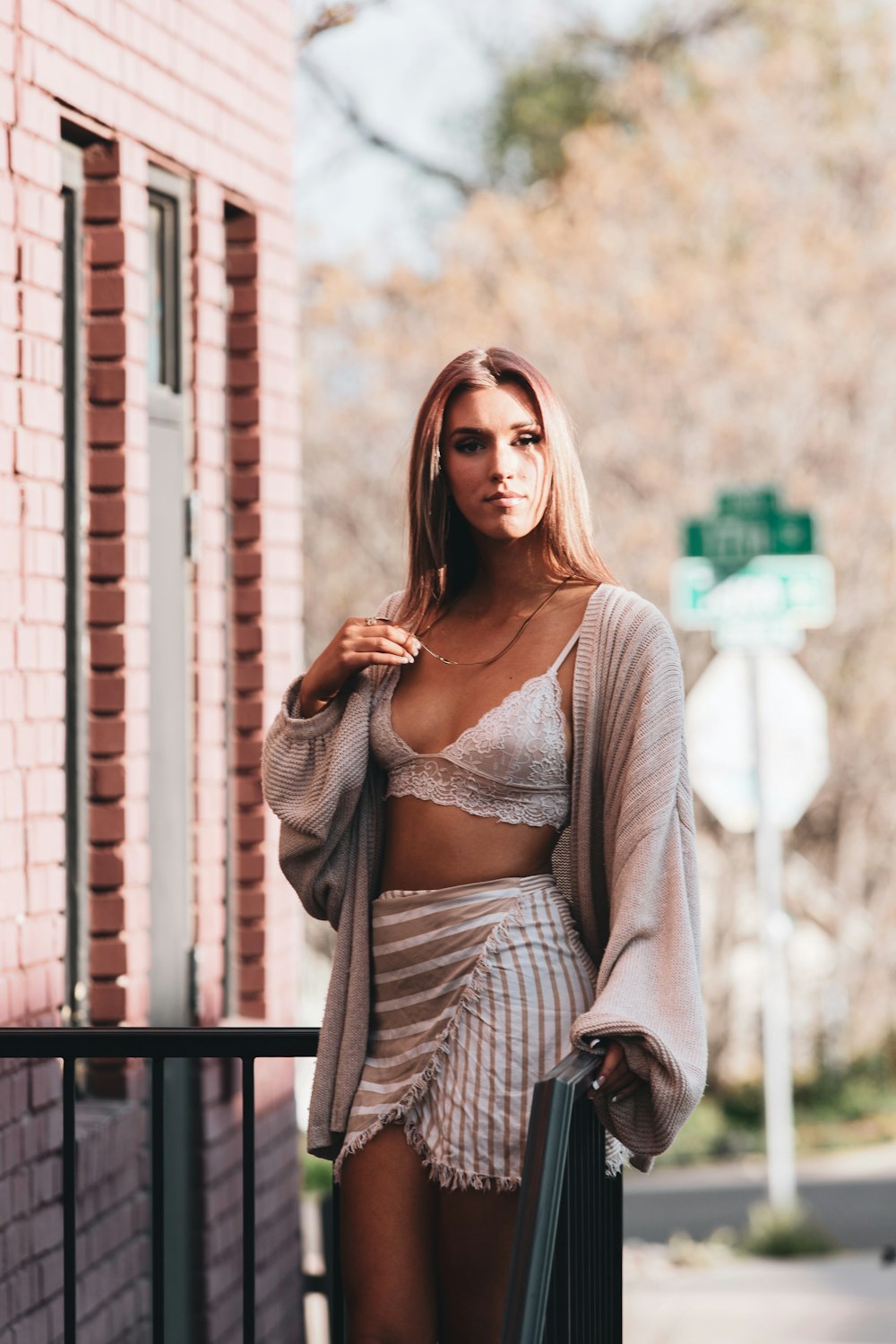 woman in gray and white striped long sleeve shirt standing beside black metal railings during daytime