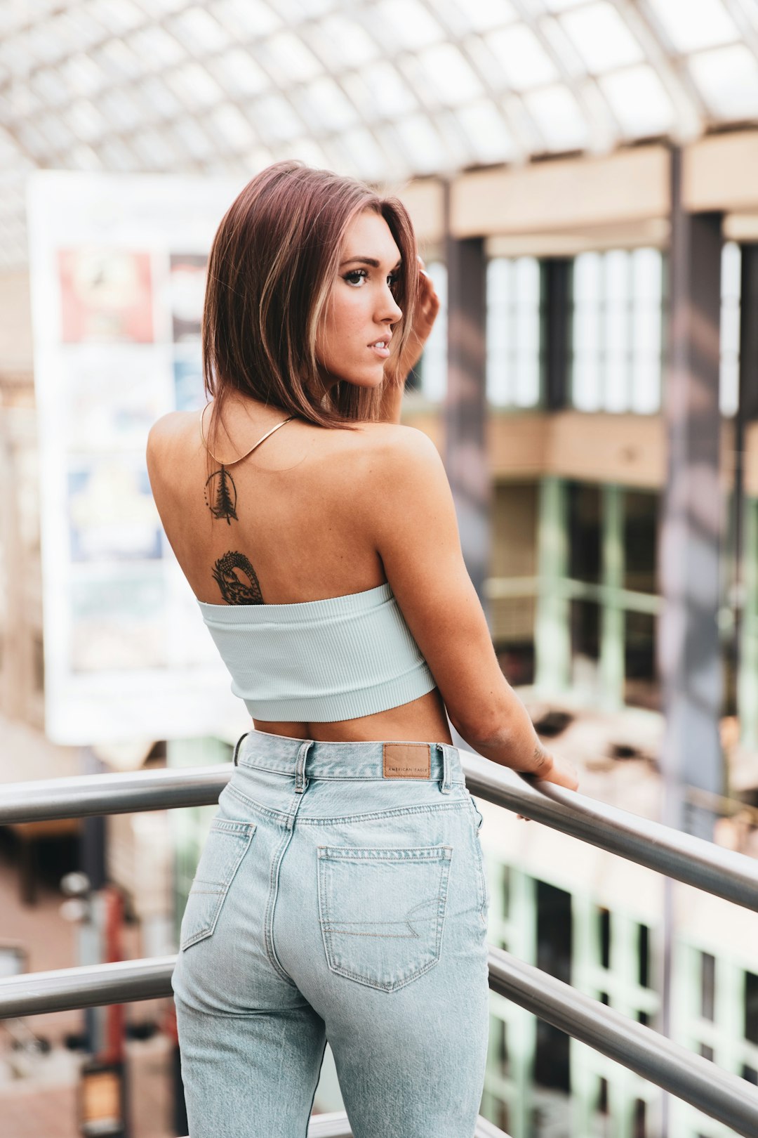 woman in white spaghetti strap crop top and blue denim shorts standing beside railings during daytime