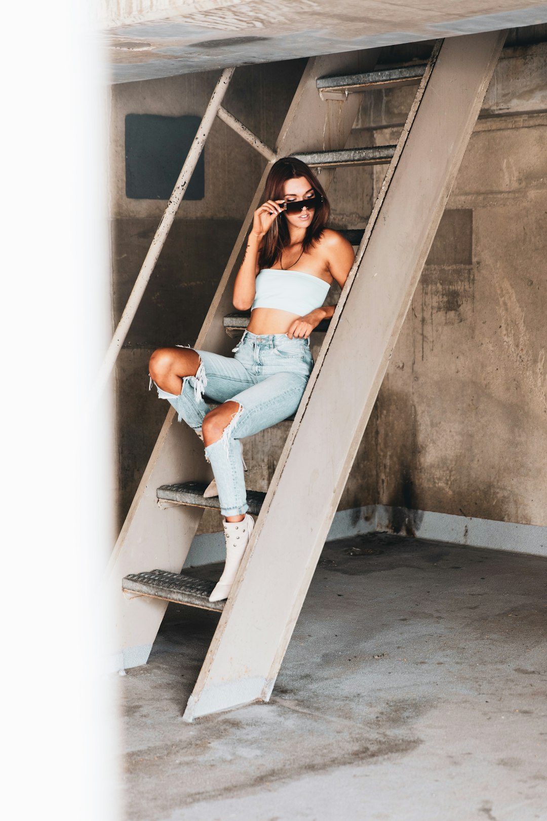 woman in blue denim jeans sitting on white concrete stairs