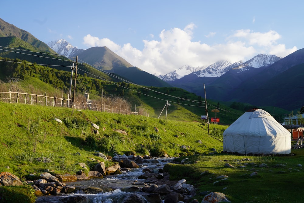 white tent on green grass field near mountain during daytime