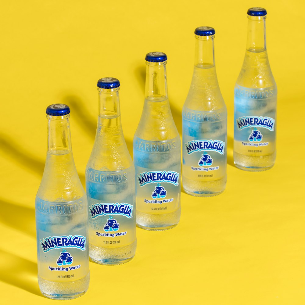 four blue labeled bottles on yellow surface