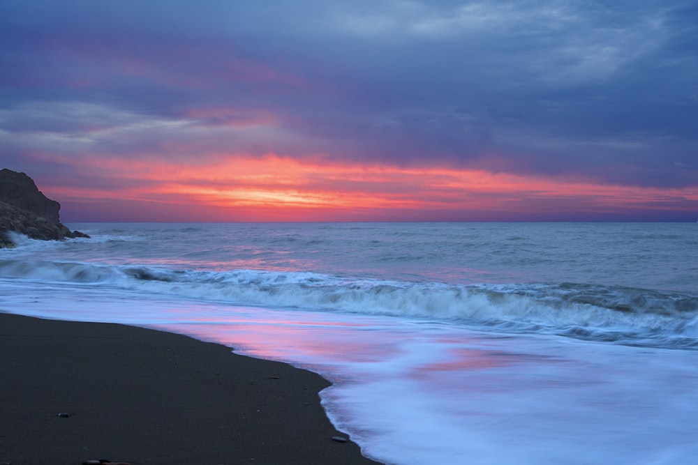 Meereswellen stürzen während des Sonnenuntergangs an Land