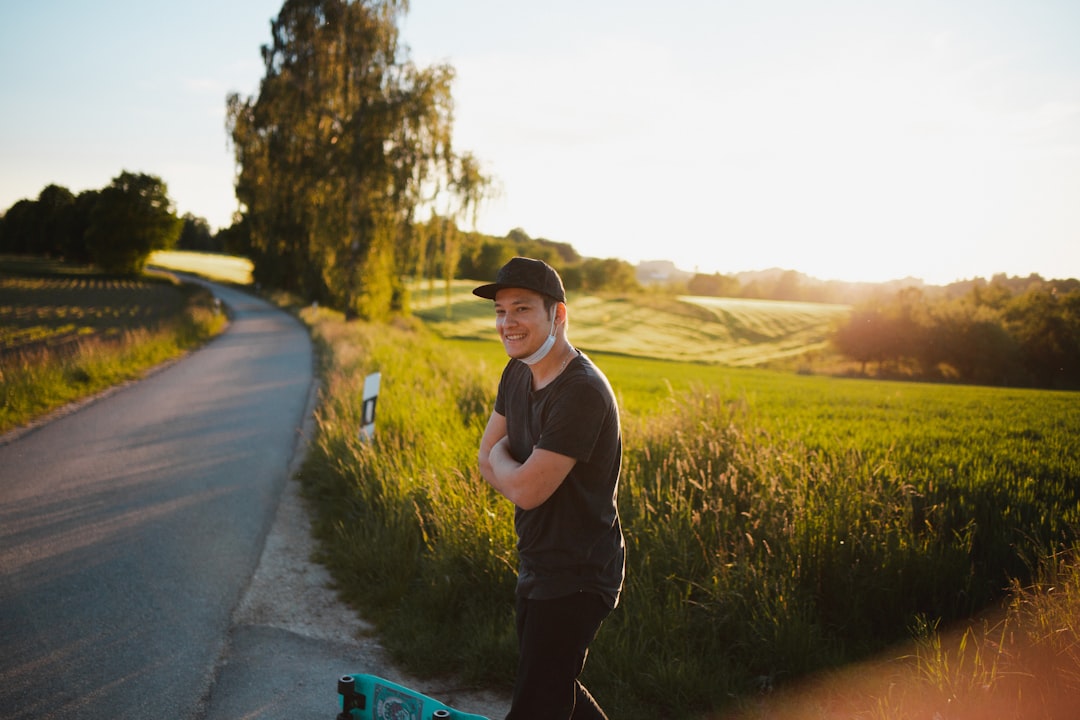 man in white t-shirt and black pants standing on road during daytime