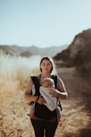woman in black tank top carrying baby