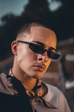 Close-up of a camera lens capturing a confident subject in a stylish outfit.
