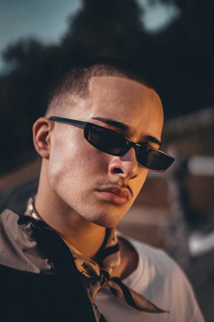 Close-up of a camera lens capturing a confident subject in a stylish outfit.