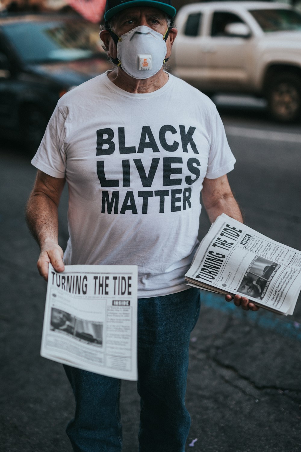 man in white crew neck t-shirt and blue denim jeans holding newspaper