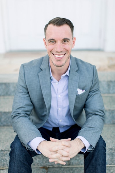 man in gray suit jacket sitting on gray concrete bench