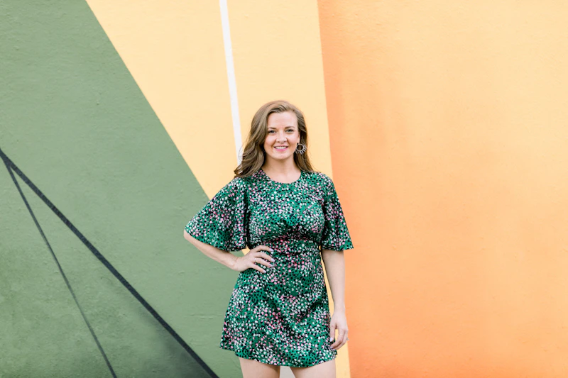 woman in floral dress by green wall
