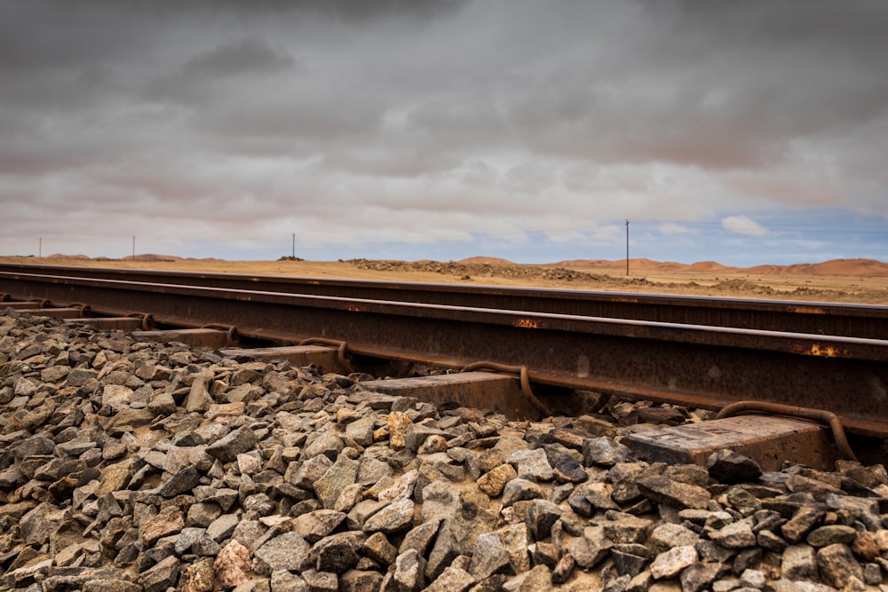 brown train rail under cloudy sky during daytime
