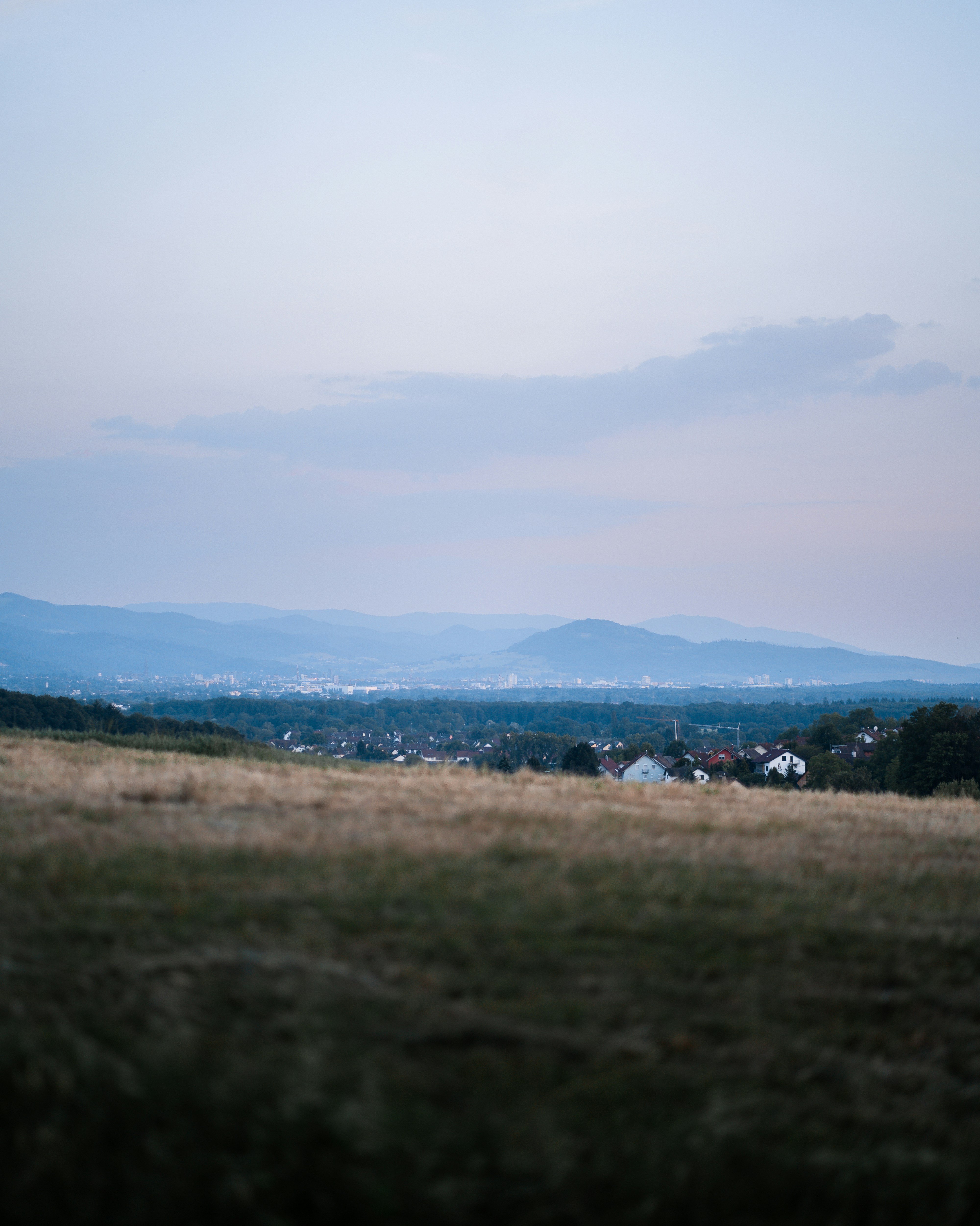 green grass field near mountain under white clouds during daytime