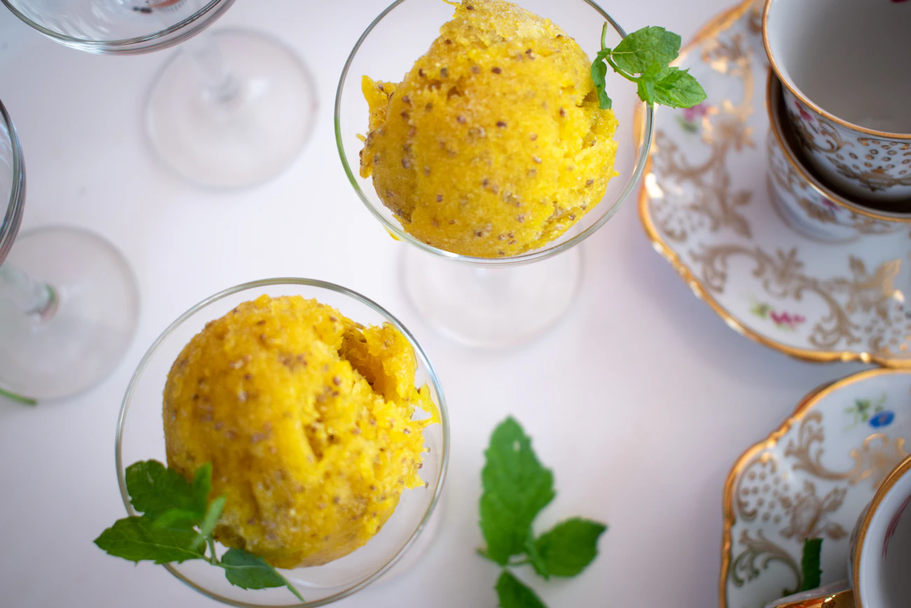 Saffron-yellow Rajbhog ice cream in glass bowls with mint