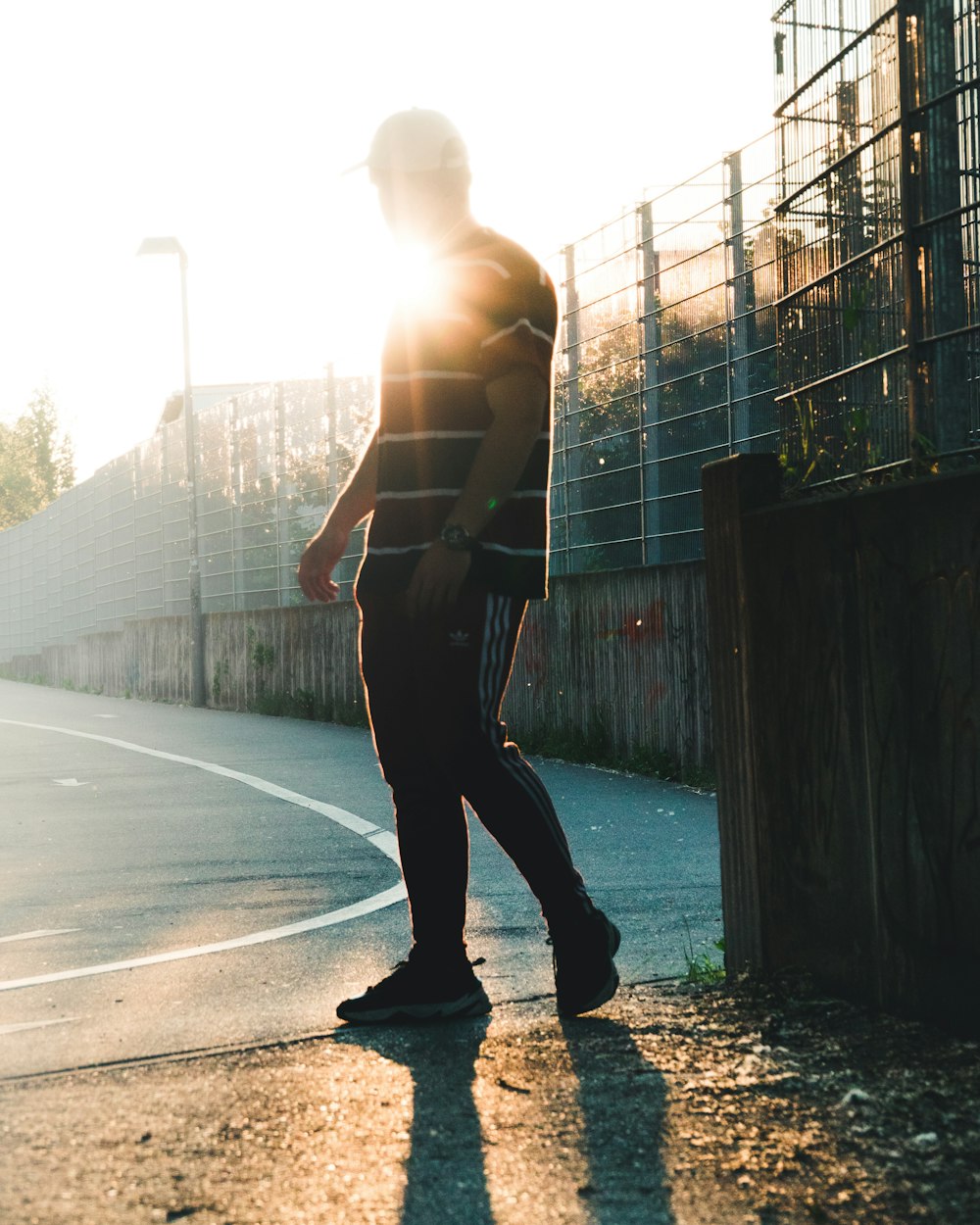 topless man in black pants and black shoes walking on sidewalk during daytime