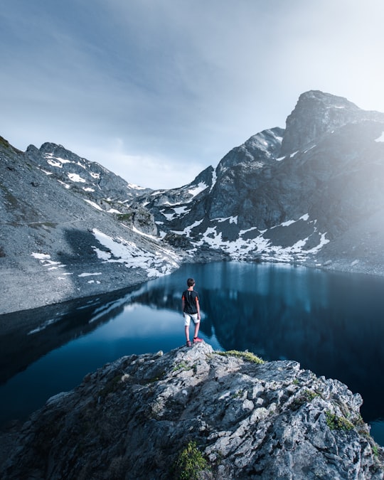 person in red jacket standing on rock near lake during daytime in Rhône-Alpes France