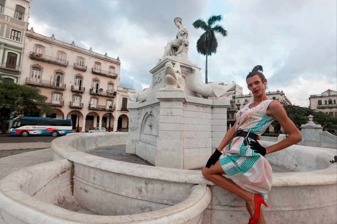 woman in white and black dress sitting on white concrete fountain during daytime