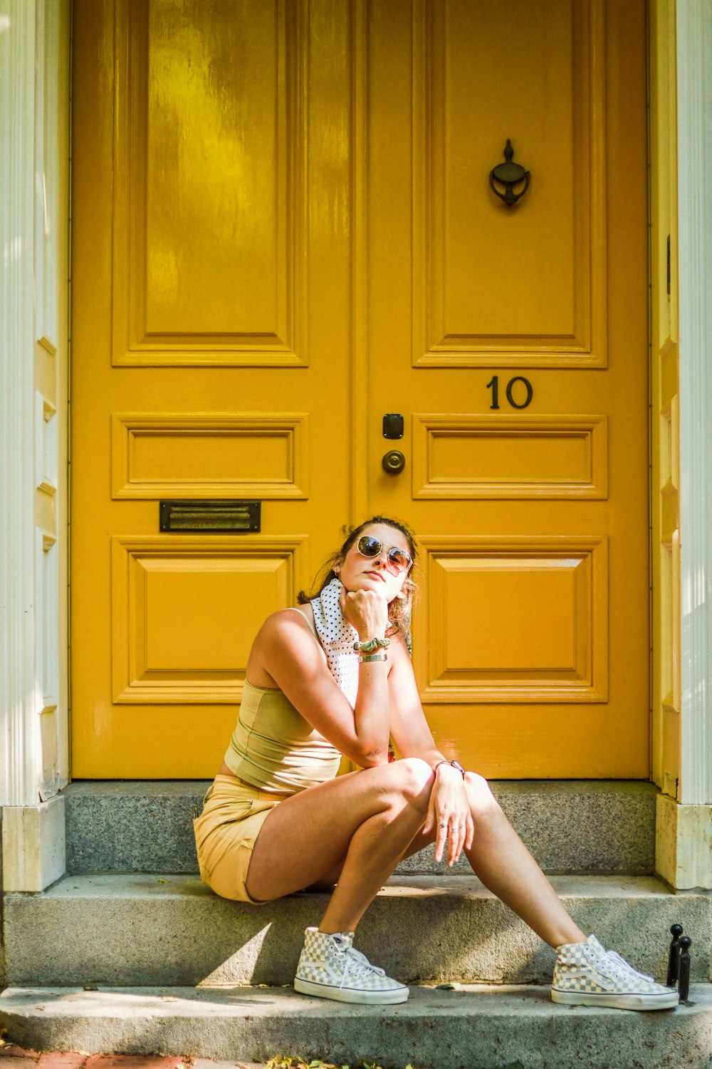 woman in brown sleeveless dress sitting on gray concrete stairs